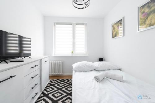 Qwadratura 28 by 3City Rentals في غدانسك: غرفة نوم بيضاء مع سرير وتلفزيون بشاشة مسطحة