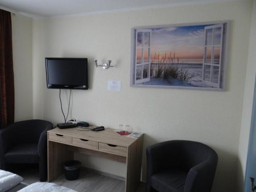 a room with two chairs and a desk with a television at Hotel zum Fährhaus in Parchim