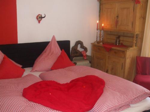 a red heart pillow sitting on top of a bed at Ferienwohnung Alpensonne in Oberstdorf