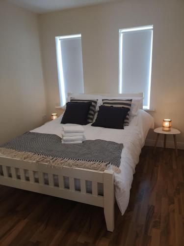 a bedroom with a white bed with two windows at Spacious and warm 2 bedroom apartment sleeps up to 5 in Athy