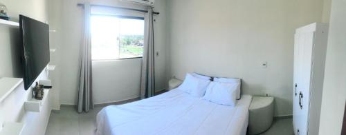 a white bedroom with a bed and a window at Departamento al lado de Fortis in Ciudad del Este