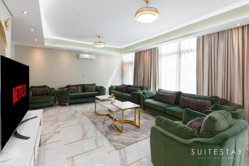 a living room with green couches and a tv at Exclusive 6 Bedroom Villa with Pool and Gym access in Dubai