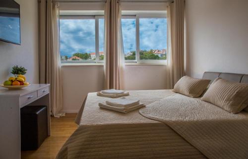 a bedroom with a large bed with two windows at Apartment Victoria II in Dubrovnik
