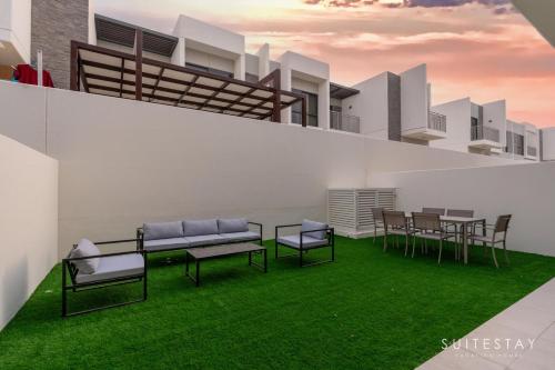 Boho Inspired Large Luxury Villa في دبي: فناء مع كراسي وطاولة وعشب