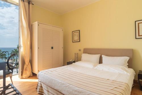 a bedroom with a large bed and a balcony at Hotel De La Plage in Pietra Ligure
