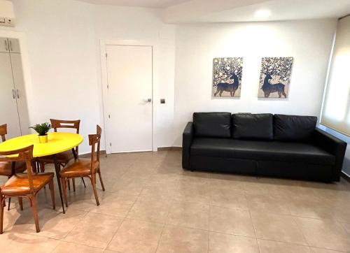 ein Wohnzimmer mit einem schwarzen Sofa und einem Tisch in der Unterkunft Torre de Romo - Más que apartamentos in Murcia