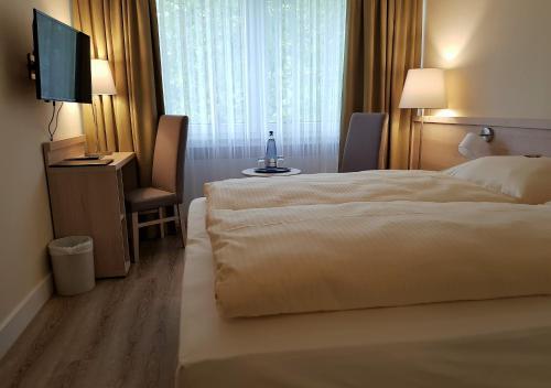 a hotel room with a bed and a flat screen tv at ParkHotel Bad Harzburg in Bad Harzburg