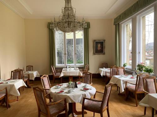 a dining room with tables and chairs and a chandelier at ParkHotel Bad Harzburg in Bad Harzburg