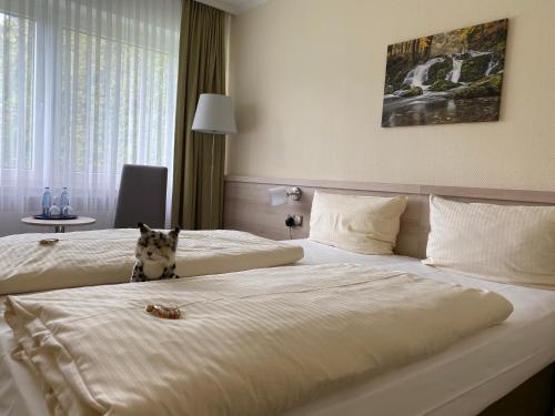a dog sitting on top of two beds in a hotel room at ParkHotel Bad Harzburg in Bad Harzburg