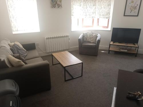 a living room with a couch and a table and a tv at Hull City Centre Accommodation 1 in Hull