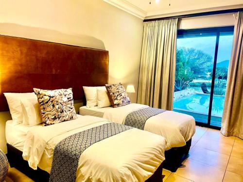 two beds in a hotel room with a balcony at Mountainview Villa in Hartbeespoort