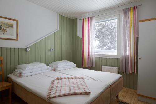 a bed in a green room with a window at Levilehto Apartments in Levi