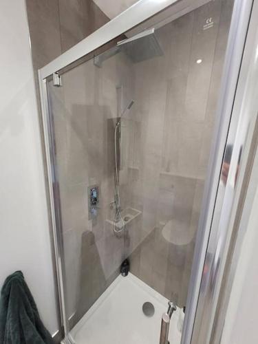 een douche met een glazen deur in de badkamer bij Tiny House in Affluent Suburb-10 min train to City in Kirkintilloch