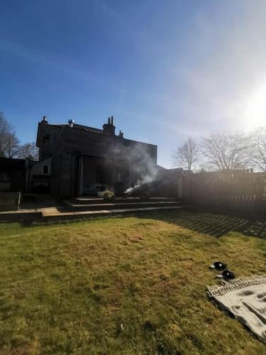 een huis met rook in een tuin bij Tiny House in Affluent Suburb-10 min train to City in Kirkintilloch