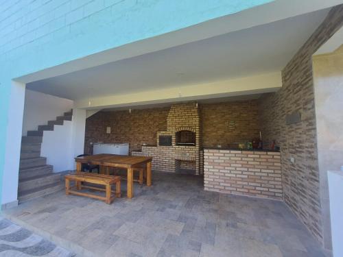 uma cozinha com uma mesa de madeira e uma parede de tijolos em Chácara ( Dona Juju) super confortável em Igarata/SP! em Igaratá