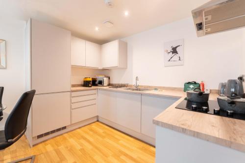 a kitchen with white cabinets and a wooden floor at Leeds City Centre Duplex 3 Bedroom 3 Bath stunning Flat with Rooftop Terrace and Parking in Leeds