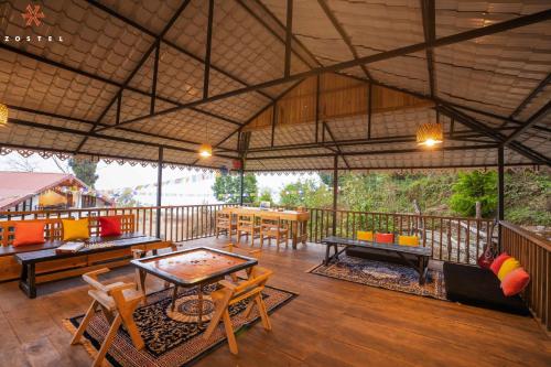 a large patio with tables and chairs on a deck at Zostel Rinchenpong (Pelling) in Rinchingpong