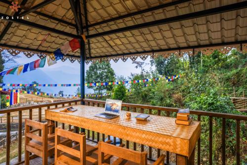 a wooden table on a balcony with a laptop on it at Zostel Rinchenpong (Pelling) in Rinchingpong