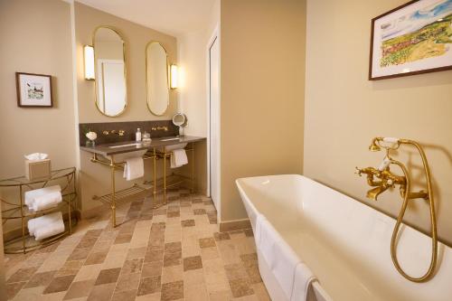 a bathroom with a tub and a sink and mirror at Maison 1896 in Beaune