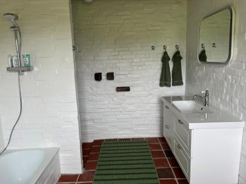 ein weißes Badezimmer mit einem Waschbecken und einem Spiegel in der Unterkunft Oustrupgård in Egtved