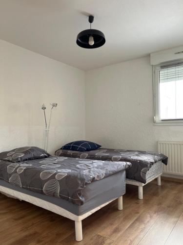 2 bedden in een slaapkamer met een plafondventilator bij Jardins Amélie in Straatsburg