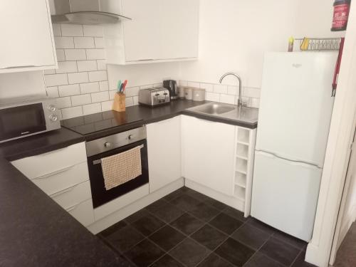 cocina con armarios blancos, fregadero y nevera en Hull City Centre Accommodation 2, en Hull