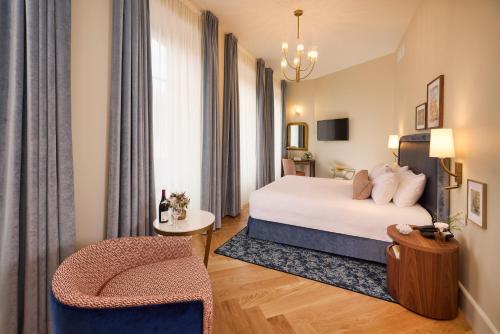 a hotel room with a bed and a chair at Maison 1896 in Beaune