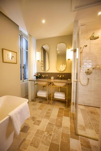 a bathroom with a tub and a shower with mirrors at Maison 1896 in Beaune