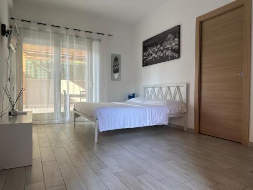 a white bedroom with a bed and a window at Mini suites in Aprilia