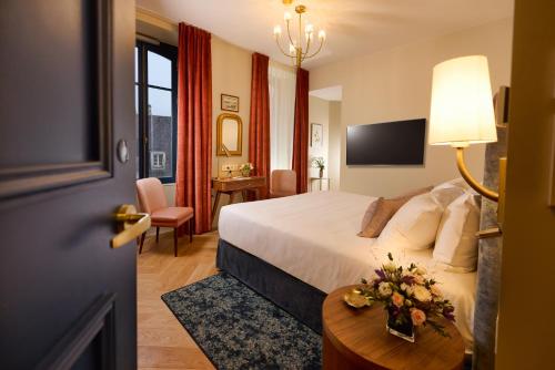 a hotel room with a bed and a table with flowers on it at Maison 1896 in Beaune