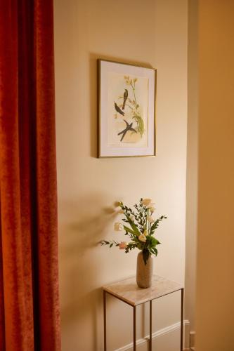 a table with a vase of flowers on a wall at Maison 1896 in Beaune