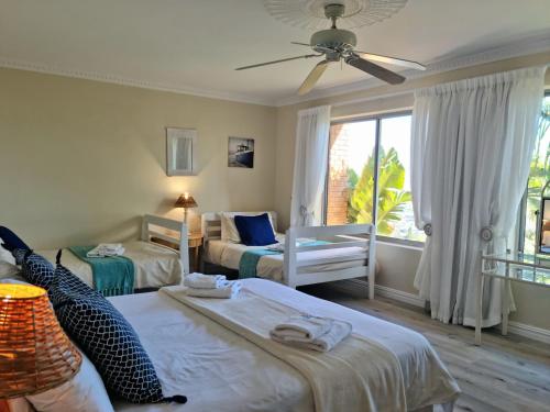 a bedroom with two beds and a ceiling fan at Summer Tides in Gordonʼs Bay