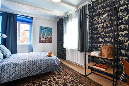a bedroom with a bed and a wall covered in wallpaper at Gite spacieux et chaleureux 8p, route des vins in Bergheim