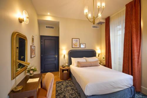 a hotel room with a bed and a desk and a mirror at Maison 1896 in Beaune