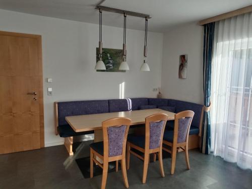 a dining room table with chairs and a blue couch at Haus Moser in Wagrain