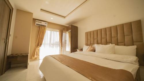 a bedroom with a large bed and a large window at The Seasons Apartment Kado in Abuja
