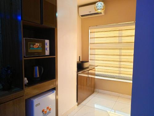 a room with a window with a television and a microwave at The Seasons Apartment Kado in Abuja