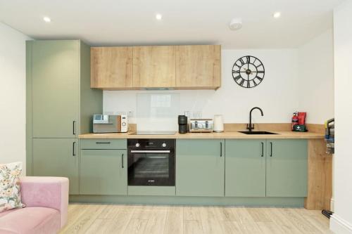 a kitchen with green cabinets and a pink couch at Stylish Beach Front Retreat in Kent