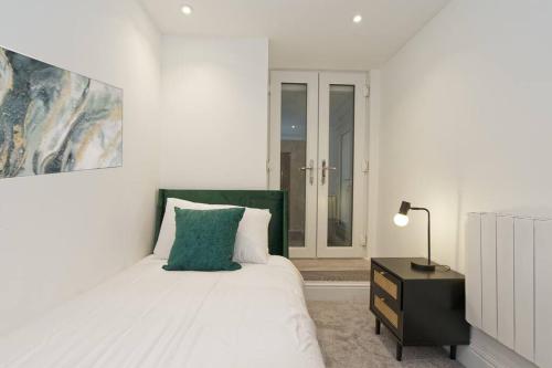 Stylish Beach Front Retreat في Kent: غرفة نوم بيضاء مع سرير مع اللوح الأمامي الأخضر