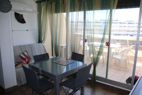 une salle à manger avec une table et des chaises et un balcon dans l'établissement Studio 34, Héliopolis E au village naturiste, au Cap d'Agde