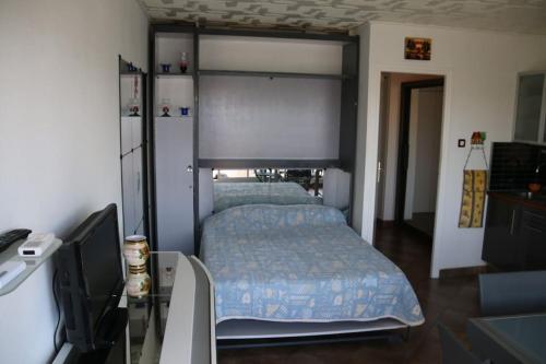Schlafzimmer mit einem Bett und einem Schreibtisch mit einem TV in der Unterkunft Studio 34, Héliopolis E au village naturiste in Cap d'Agde