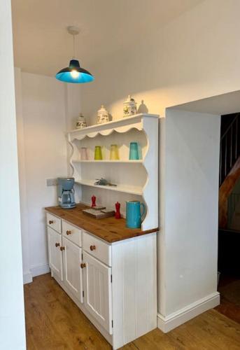 a kitchen with white cabinets and a blue light at Historic 'Old Toll House' Shaldon Bridge in Teignmouth