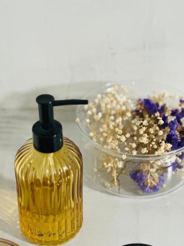 a yellow bottle sitting next to a bowl of flowers at Meliora Suites in Drapaniás
