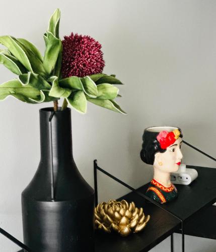a black vase with a flower and a doll on a table at Meliora Suites in Drapaniás