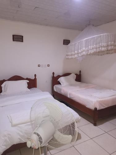 a bedroom with two beds and a fan on the floor at Alink chinese and korean restaurent in Kigali