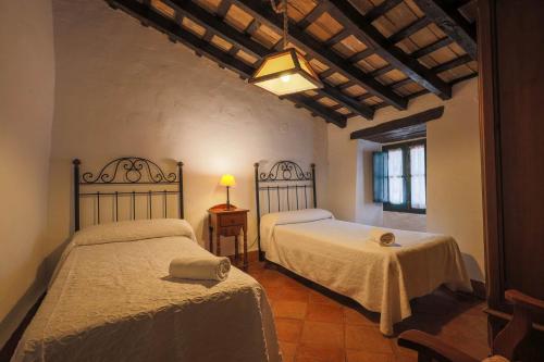 1 dormitorio con 2 camas y mesa con lámpara en Casas Rurales Tugasa Castillo de Castellar, en Castellar de la Frontera