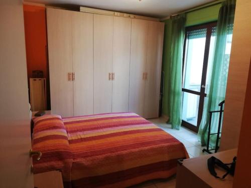 een slaapkamer met een bed, groene gordijnen en een raam bij Attico luminoso I colori del sole in Montesilvano