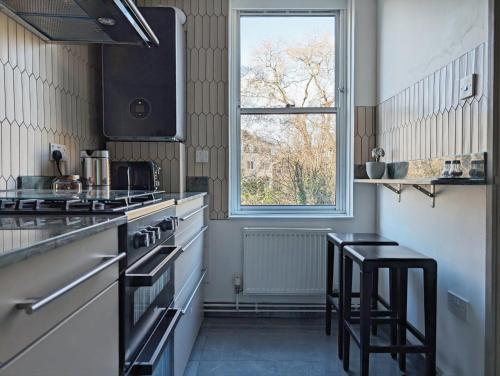 una cocina con 2 taburetes y una ventana en Riverside apartment in Islington, en Londres