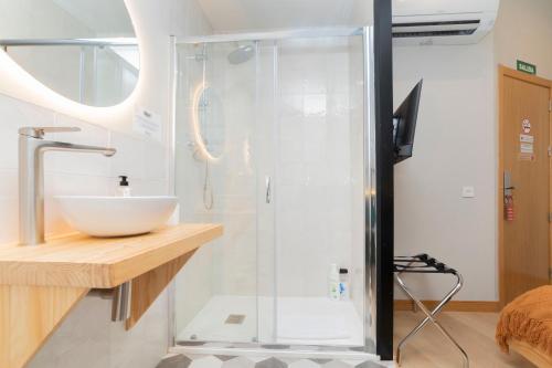 a bathroom with a glass shower with a sink at OLBLANC Plaza de España by Batuecas in Madrid