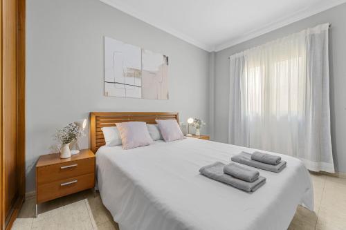 Un dormitorio blanco con una cama grande con toallas. en Piso Don Eduardo 2, en Arrecife